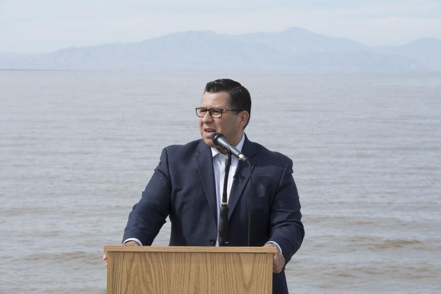 Assemblymember E Garcia standing at podium in front of Salton Sea
